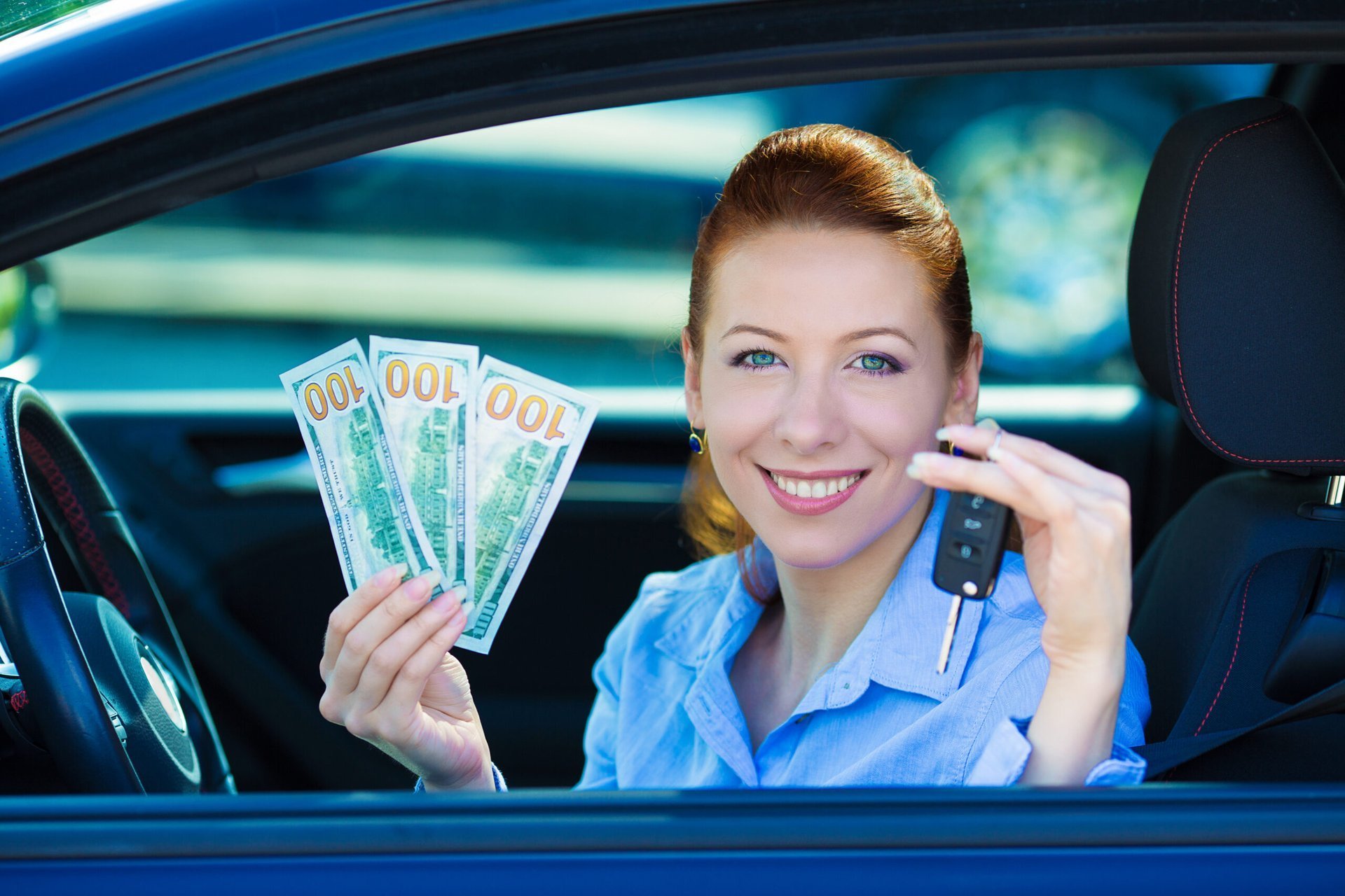 Woman in a car holding up money